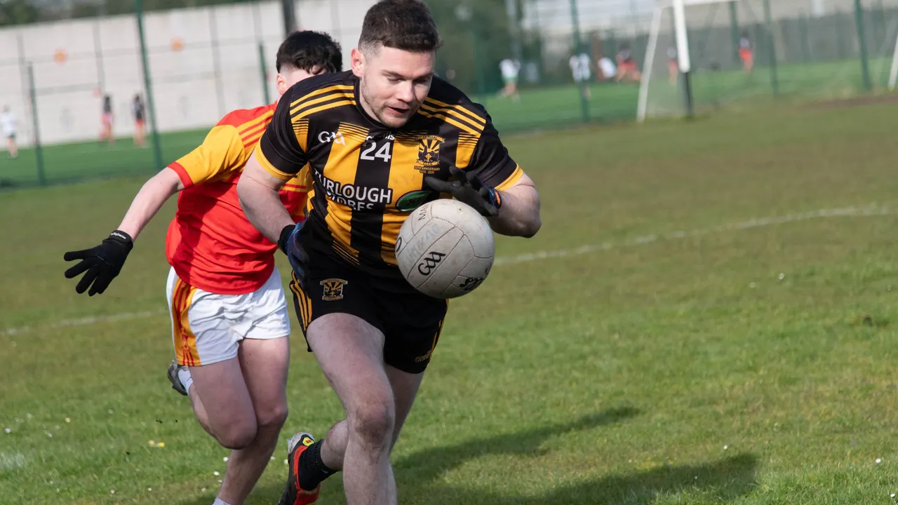 Player in black and amber gathering the ball under pressure