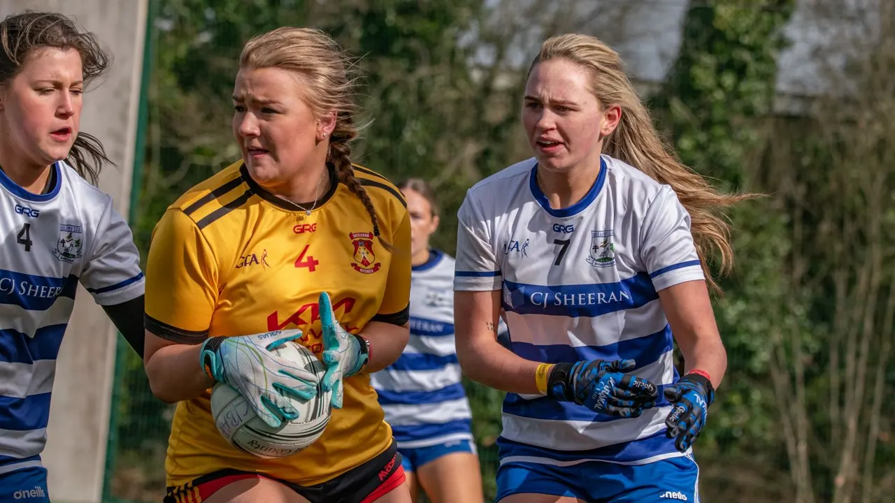 Ladies player in gold carrying the ball between two defenders
