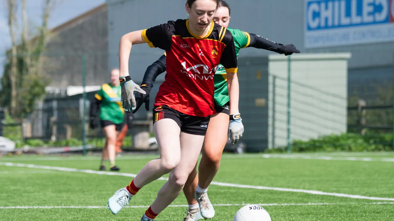Ladies player in red and black chasing the ball