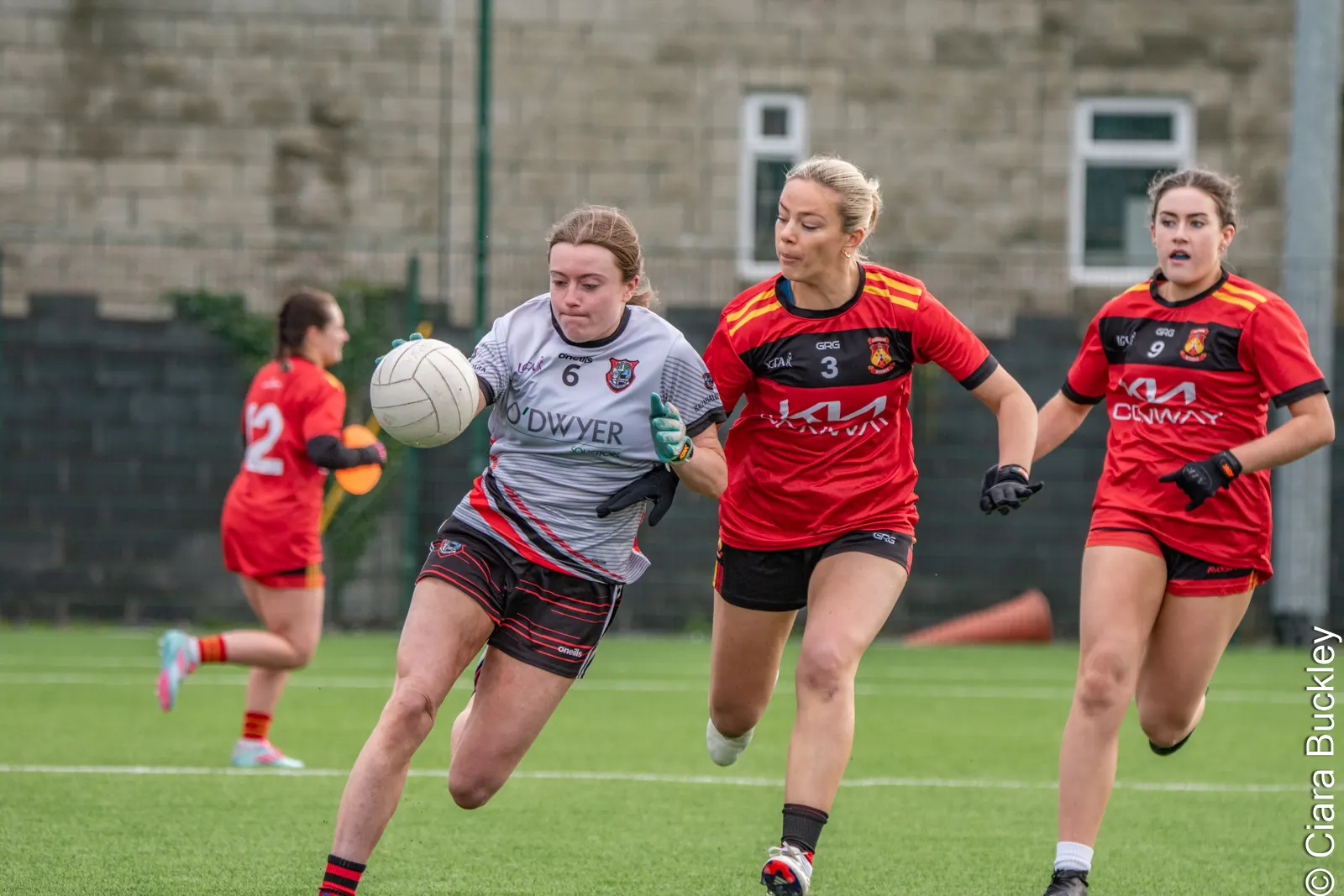 Player in grey running with the ball, chased by players in red and black